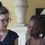 La maestra alemana enseña a otra alumna detalles para mejorar el canto